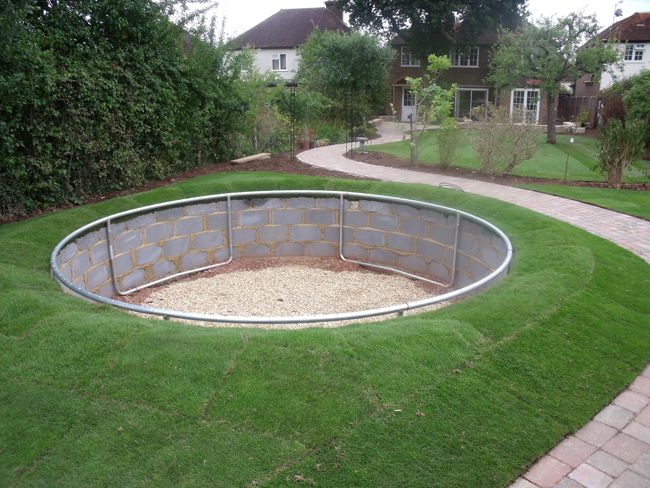Round in-ground pool shell under construction with metal wall panels set into a lawn and gravel base inside the pool.