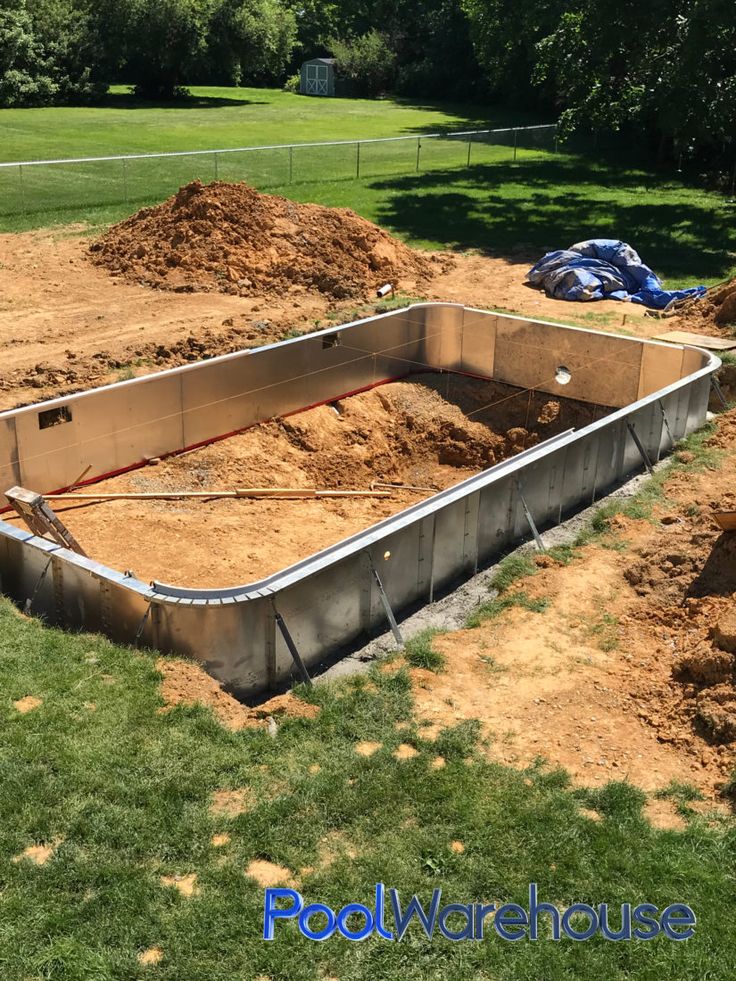 Rectangular in-ground pool kit under construction with metal wall panels installed in an excavated backyard.