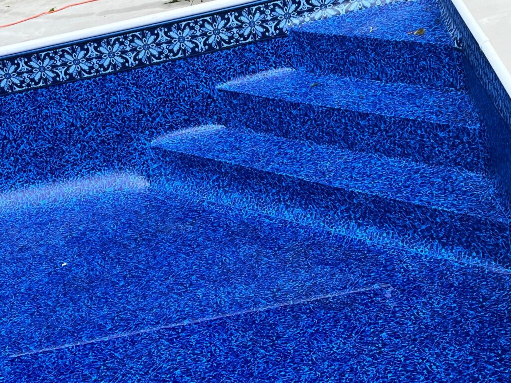 Close-up of blue patterned vinyl pool liner with built-in entry steps at the shallow end.