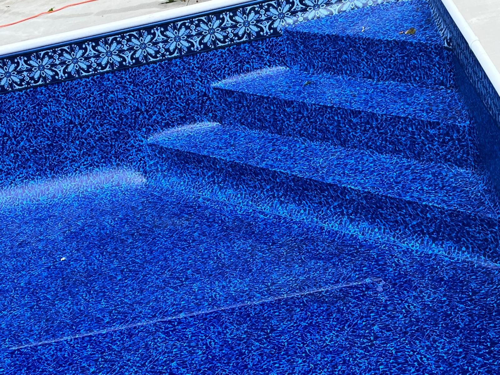 Close-up of blue patterned vinyl pool liner with built-in entry steps at the shallow end.